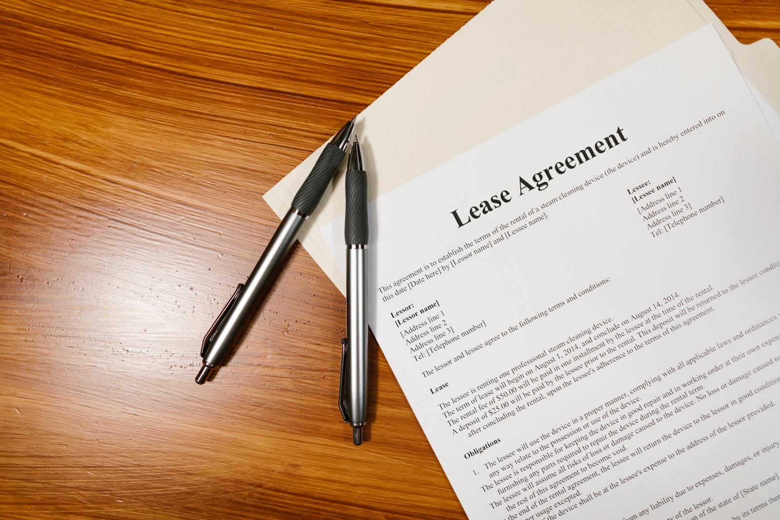 A lease agreement and two pens on a wooden desk