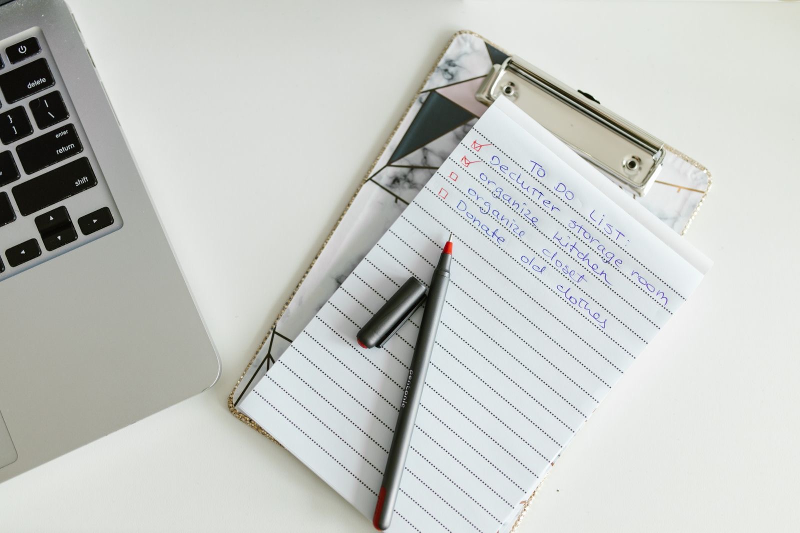 A hand with a pen checking printed documents against a list on a desk