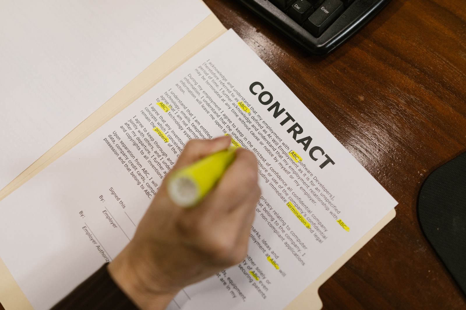 A hand highlighting lines of a printed contract