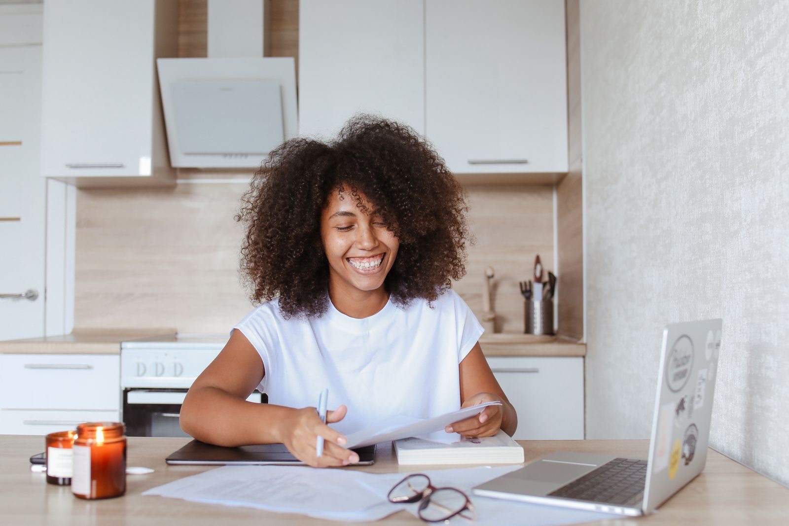 A founder working at a kitchen table with a laptop and a pile of papers