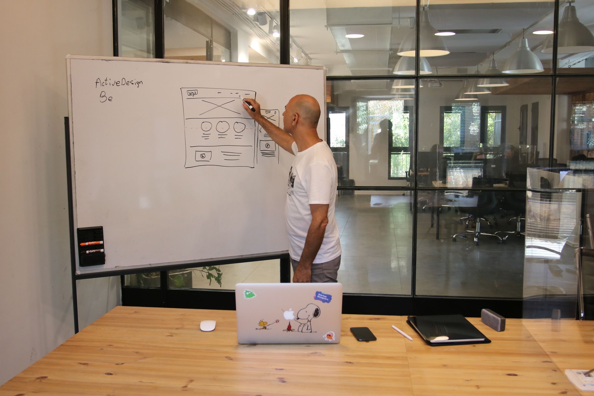 A founder at a laptop beside a whiteboard in a bright office, canal houses through the window